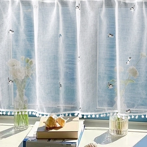 Sheer white cafe curtain with embroidered black and white cats and pom-pom trim detail