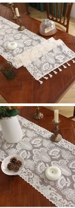 Close-up of vintage white lace table runner with hollow floral crochet and fringe details