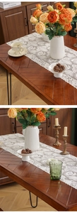 Detailed macro view of white floral lace table runner with wave edges on a wooden table
