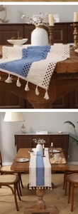 Detailed knit texture and tassels of a blue and white crochet table runner on wood