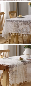 Close-up of white floral lace tablecloth with intricate crochet patterns and tassel fringe