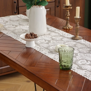 Retro hollow lace table runner with floral crochet pattern on a dark wood table