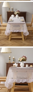 Close-up of minimalist rectangular lace tablecloth with cat embroidery and ruffled edges