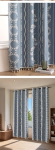 Detail of grey-blue blackout curtain with white floral patterns and cream fringe tassels