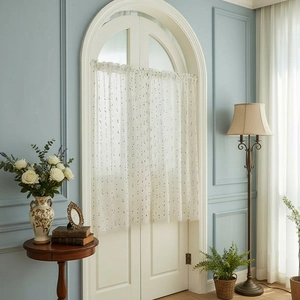 Detail of white semi-sheer lace cafe curtain with black polka dots on an arched door