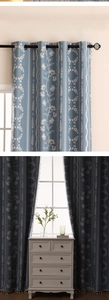 Detail of blue blackout curtains with white floral patterns and elegant tassel fringe