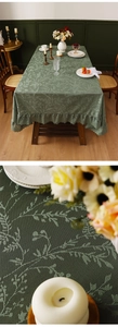 Detail of dark green lace tablecloth featuring vintage floral jacquard and ruffled edges