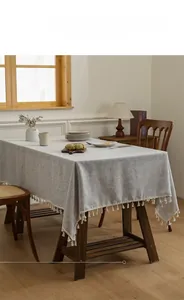 Detail of grey slub linen tablecloth featuring decorative cream fringe tassels on the edge