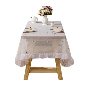 Grey minimalist tablecloth with cat embroidery and ruffled lace edges on wooden table