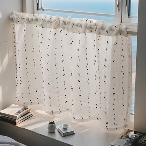 Semi-transparent white linen cafe curtain with colorful polka dots in a bright window setting