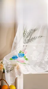 Detail of floral embroidery on white lace cafe curtain with delicate mesh texture