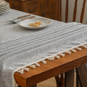 Grey linen blend tablecloth with white tassel edges on wooden table for dining decor