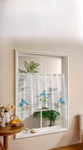 Detail of white lace cafe curtain with rose embroidery and elegant scalloped edge