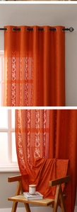 Detail of bohemian orange lace curtain with grommet top and elegant floral stripes texture