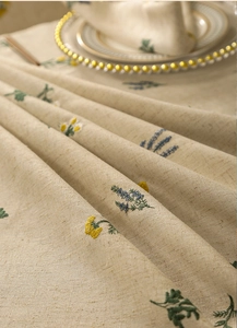 Close-up of linen tablecloth featuring floral embroidery and natural texture details