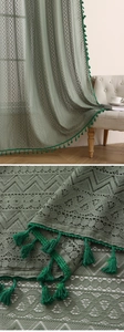 Detail of green lace curtain featuring hollow crochet patterns and decorative fringe tassels