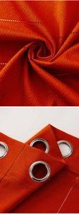 Close-up of orange striped sheer curtain fabric texture and silver metal grommet detail