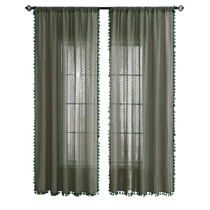 Dark green lace curtains with hollow embroidery and tassel fringe hanging on a black rod