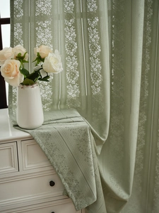Detail of pea green lace curtain featuring delicate floral hollow embroidery design
