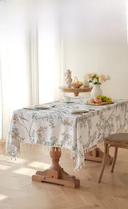 Detail of floral and bird print tablecloth with elegant white fringe tassel edges