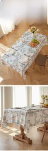 Detail of floral and bird print tablecloth with elegant white fringe tassels on the edges