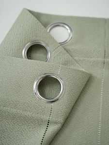 Detail of light green sheer curtain showing silver metal eyelets and textured vertical stripes