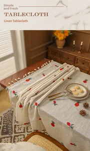 Close-up of beige linen tablecloth with red strawberry embroidery and beige tassels