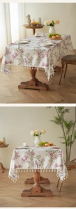 Detail der Tischdecke mit Blumen- und Vogelmuster und eleganten weißen Quasten