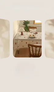Detailed view of linen tablecloth with white tassels and red strawberry embroidery