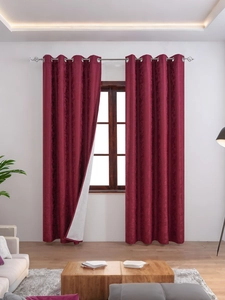 Detail of burgundy blackout curtain with elegant floral texture and silver grommets