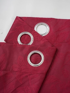 Detail of burgundy blackout curtains with textured jacquard pattern and silver metal eyelets