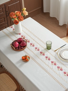 Detailed close-up of geometric diamond embroidery and tassel fringe on a luxury tablecloth