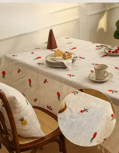 Close-up of linen tablecloth with fruit embroidery and decorative fringe trim