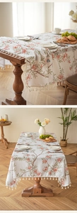 Detail der Blumen-Vogel-Tischdecke mit eleganten weißen Fransen auf einem Holztisch