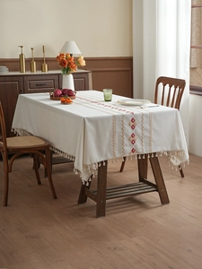 Detail of cream tablecloth with red-gold geometric diamond embroidery and fringe
