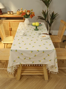 Detail of beige tablecloth with yellow floral embroidery and white fringe tassels