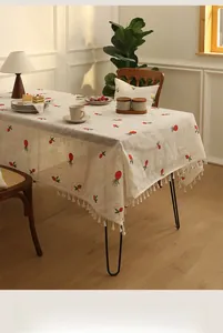 Close-up of linen blend tablecloth with red strawberry embroidery and white tassels