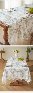 Detail der floralen Leinentischdecke mit weißen Quasten und natürlichem Holzdekor