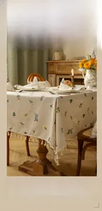 Detailed macro view of pastoral floral tablecloth with white cotton fringe tassels