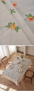 Close-up of cream cotton linen tablecloth with yellow floral embroidery and tassel fringe