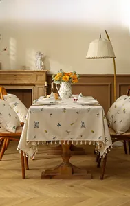 Close-up of floral embroidery and white tassel fringe on cream linen tablecloth
