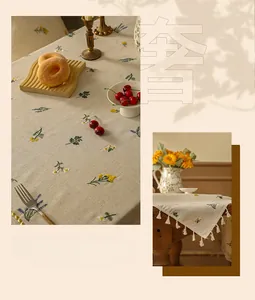 Close-up of beige linen tablecloth with daisy floral embroidery and elegant tassels