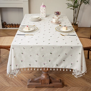 Waterproof linen tablecloth with pink floral embroidery and fringe tassels on a dining table