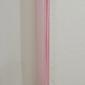 Detail view of pink folding partition curtain showing the textured flexible pleats