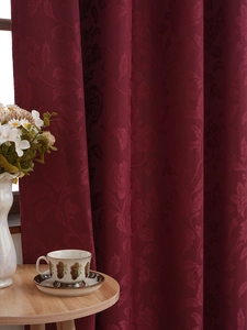 Detail of wine red blackout curtain with luxury floral jacquard and natural drape texture