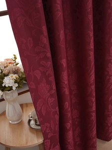 Close-up of luxury burgundy curtains with elegant floral jacquard patterns in a living room