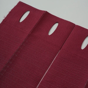 Détail macro de la texture du tissu rouge vin avec des trous ovales pour rideaux pliants