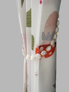 Detail of elegant shell and gold bead tieback on printed folding partition curtain