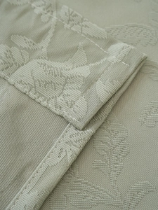 Detailed close-up of sage green jacquard fabric featuring elegant leaf pattern and stitching
