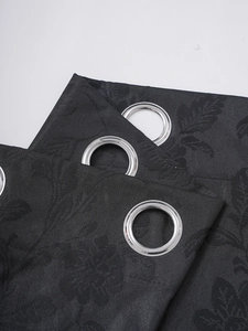 Detail of black blackout curtain with leaf texture and silver metal grommets